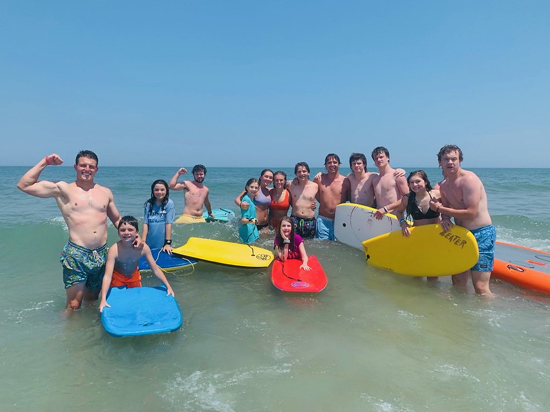 Kids with boogie boards and floats in the ocean.